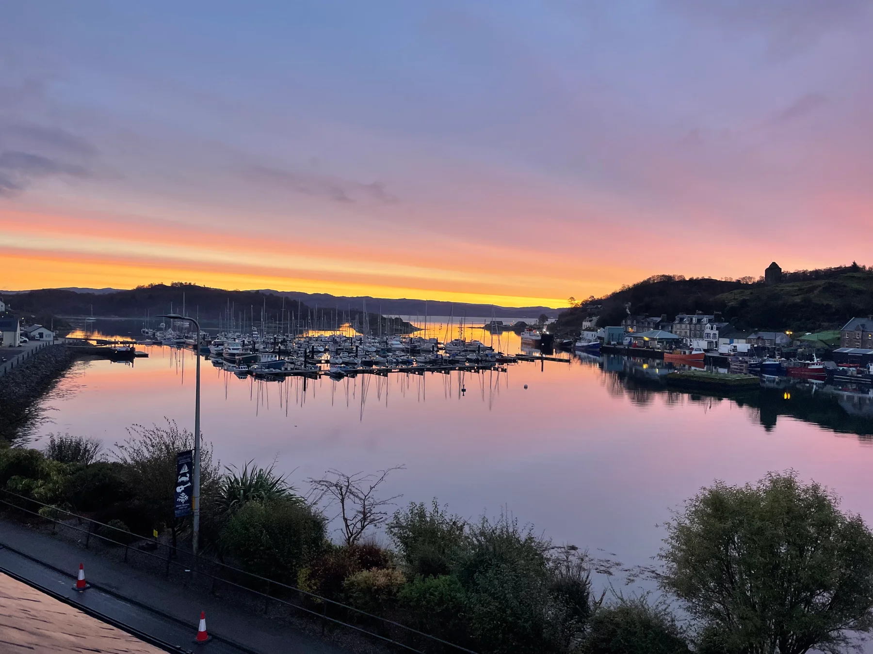 Boats in Tarbert harbour beneath a pink and orange sunset
